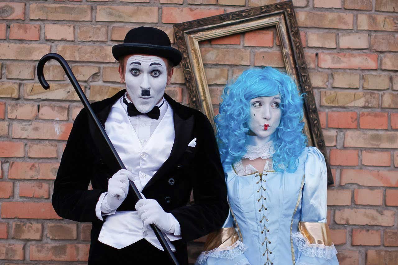 Wenn Stummfilm auf Märchen trifft. Pantomime-Walk Act mit Charlie-Chaplin- und Malvina-Charakteren vor Backsteinwand für Events in Hamburg.